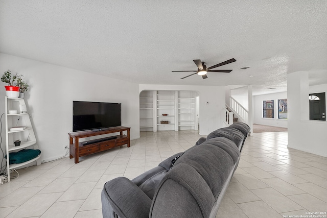 living room with ceiling fan, light tile patterned flooring, and a textured ceiling