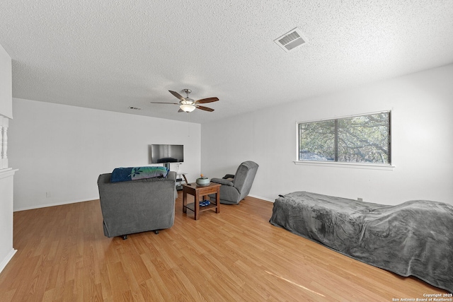 bedroom featuring ceiling fan, a textured ceiling, and light hardwood / wood-style floors