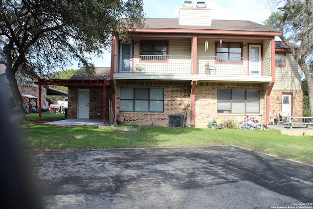 view of front of house featuring a carport, a balcony, and a front yard