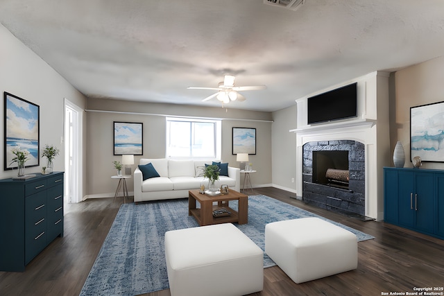 living room with a tile fireplace, ceiling fan, and dark wood-type flooring