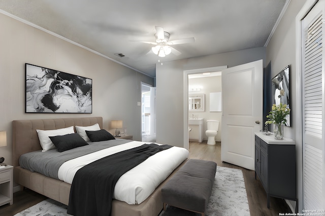 bedroom featuring ceiling fan, ornamental molding, dark wood-type flooring, and connected bathroom