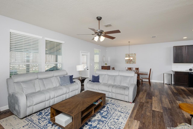 living room featuring a textured ceiling, dark hardwood / wood-style floors, and ceiling fan with notable chandelier