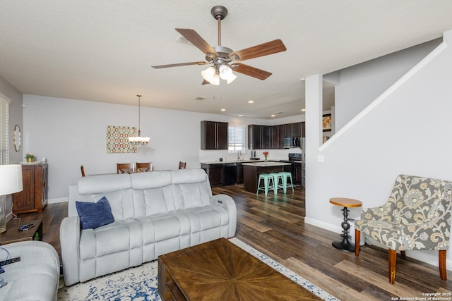 living room featuring dark hardwood / wood-style floors and ceiling fan with notable chandelier