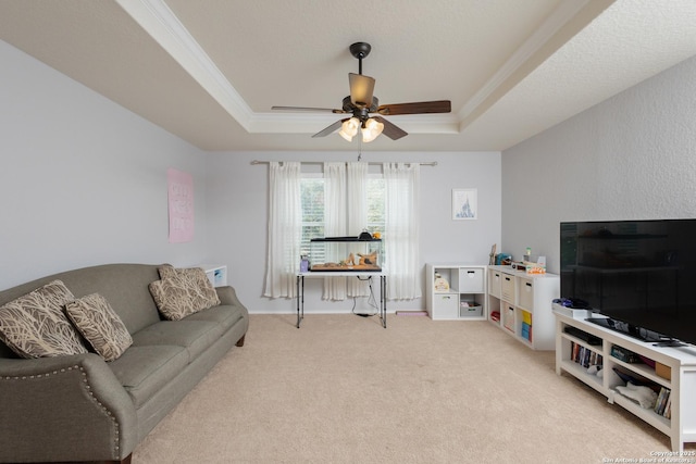 carpeted living room featuring crown molding, a tray ceiling, and ceiling fan