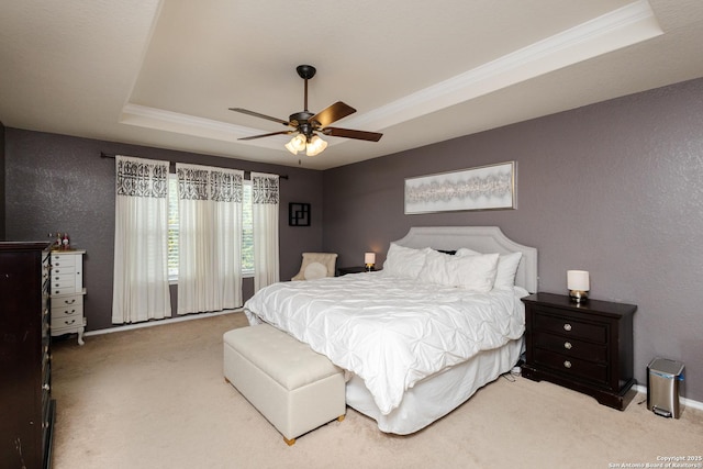 bedroom with ceiling fan, ornamental molding, a raised ceiling, and light colored carpet