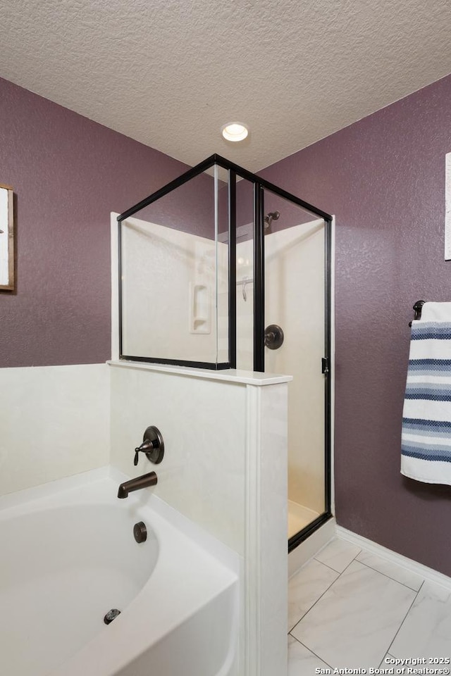 bathroom featuring a textured ceiling and separate shower and tub