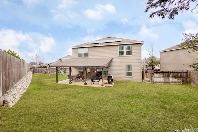 back of house with a patio, solar panels, and a lawn