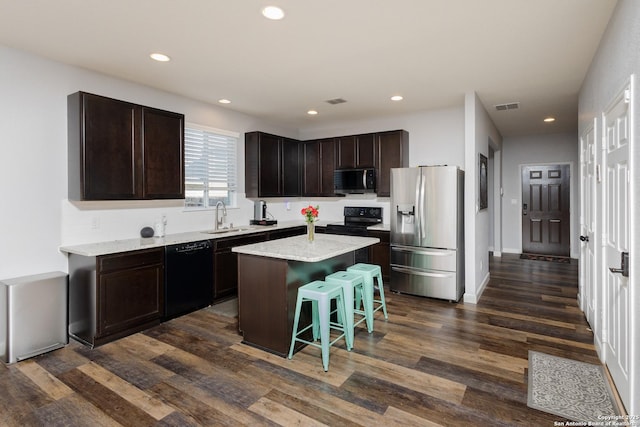 kitchen with dark hardwood / wood-style floors, a kitchen island, black appliances, sink, and a breakfast bar area