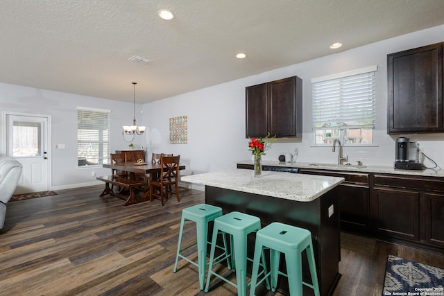 kitchen with sink, a kitchen breakfast bar, a kitchen island, dark wood-type flooring, and dark brown cabinetry