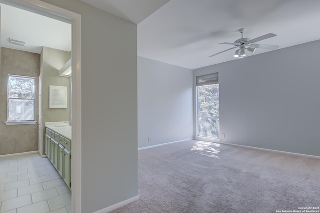 spare room featuring visible vents, baseboards, a ceiling fan, and light colored carpet