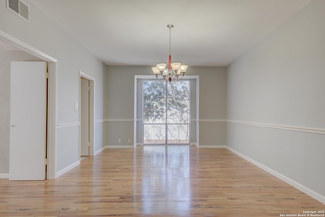 unfurnished dining area featuring an inviting chandelier, light wood-style flooring, visible vents, and baseboards