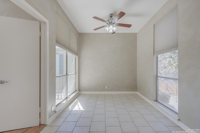 unfurnished room with light tile patterned floors, a ceiling fan, and baseboards