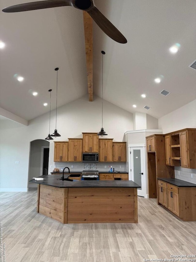 kitchen featuring beamed ceiling, light wood-type flooring, stainless steel appliances, and hanging light fixtures