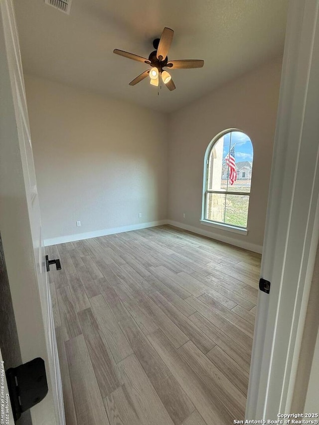 empty room with ceiling fan and light hardwood / wood-style flooring