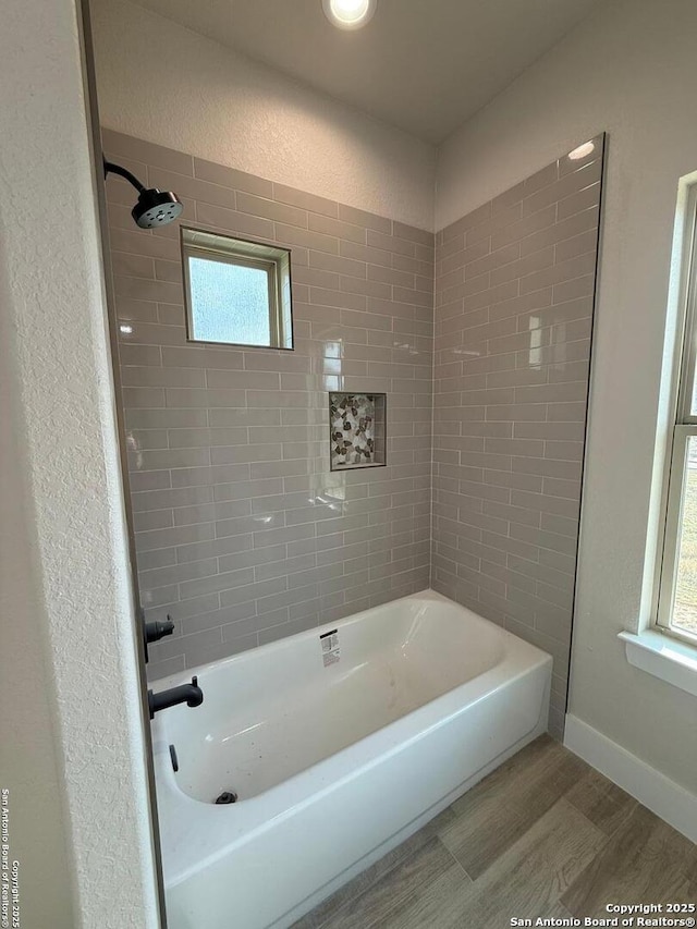 bathroom with hardwood / wood-style flooring and tiled shower / bath combo