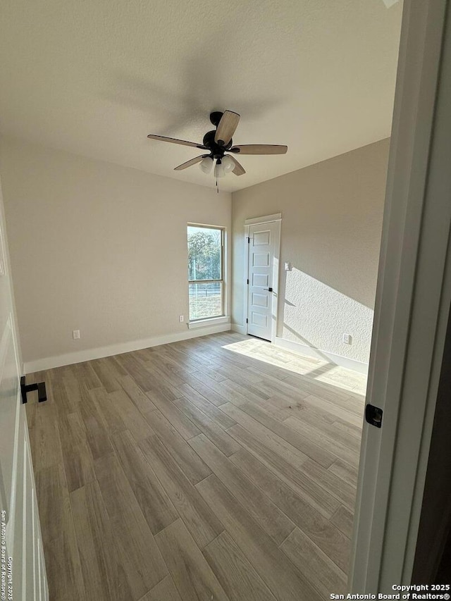 unfurnished room with ceiling fan, light hardwood / wood-style floors, and a textured ceiling