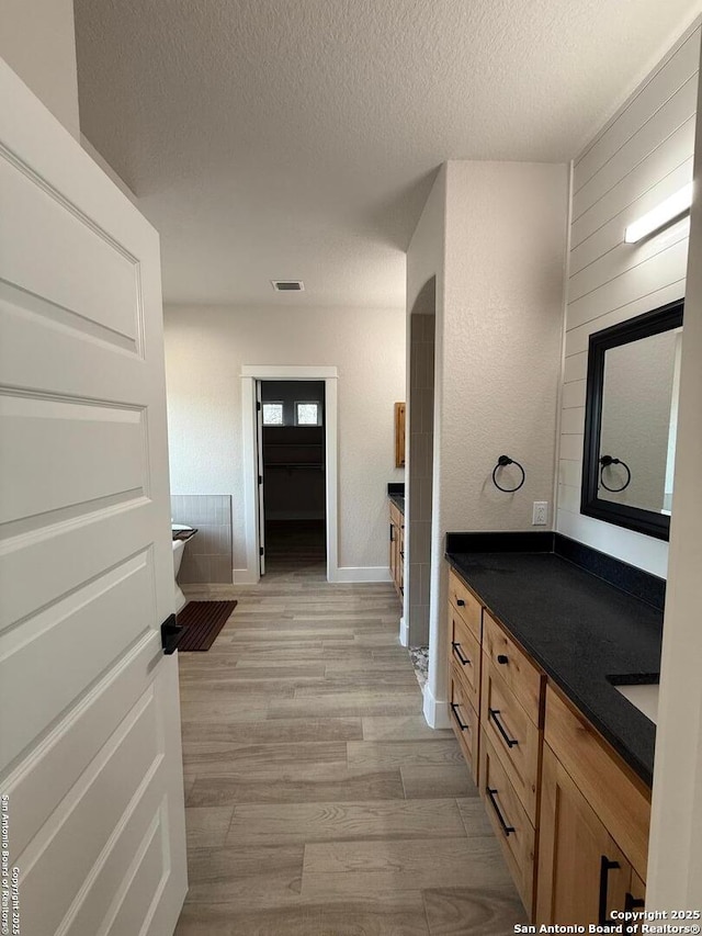 bathroom featuring vanity, wood-type flooring, and a textured ceiling