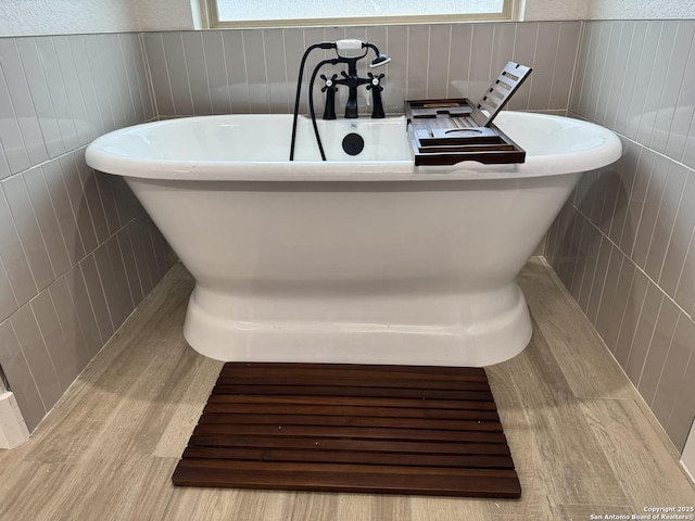 bathroom featuring tile walls, a washtub, and a wealth of natural light