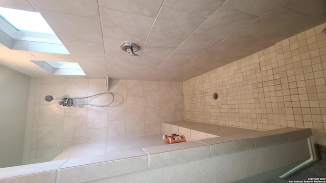 bathroom with a tile shower and a skylight