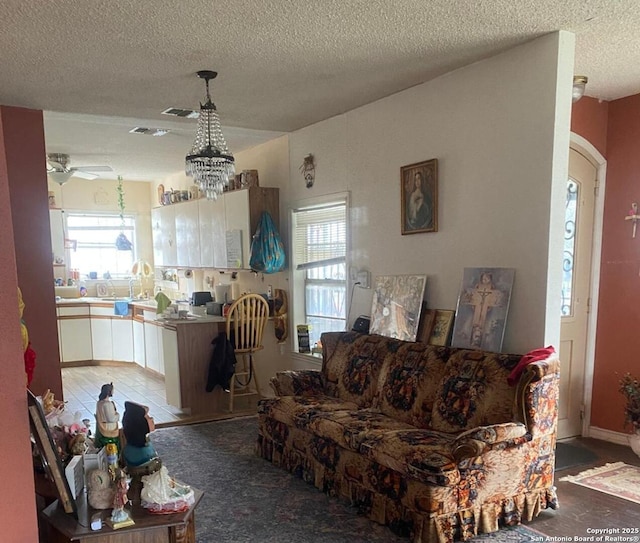 living room featuring a healthy amount of sunlight, sink, a textured ceiling, and ceiling fan