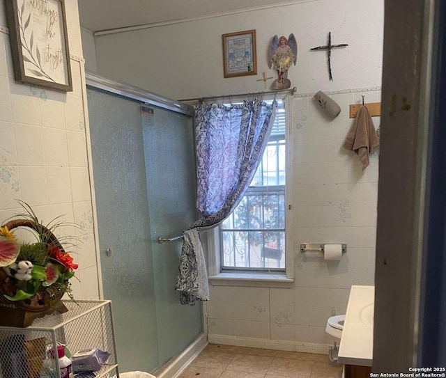 bathroom featuring tile patterned flooring, toilet, tile walls, vanity, and walk in shower