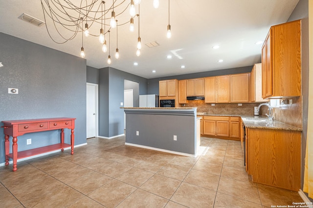 kitchen with white fridge, sink, a kitchen island, light stone countertops, and tasteful backsplash