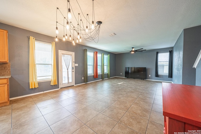 unfurnished living room with ceiling fan with notable chandelier, light tile patterned floors, and a textured ceiling