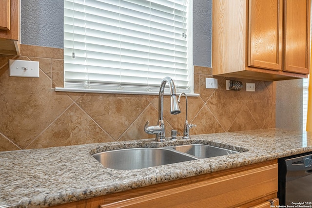 kitchen with sink, black dishwasher, light stone countertops, and tasteful backsplash