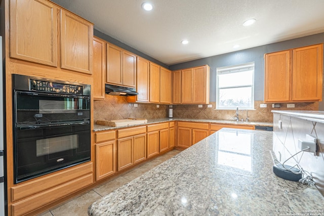 kitchen with double oven, light tile patterned floors, light stone countertops, and decorative backsplash