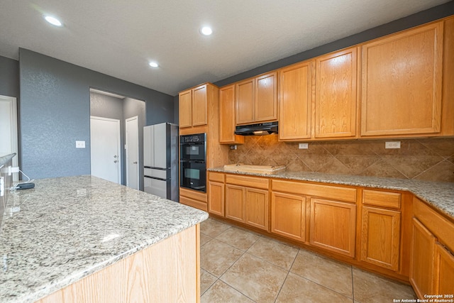 kitchen featuring extractor fan, black double oven, stainless steel fridge, and light stone countertops