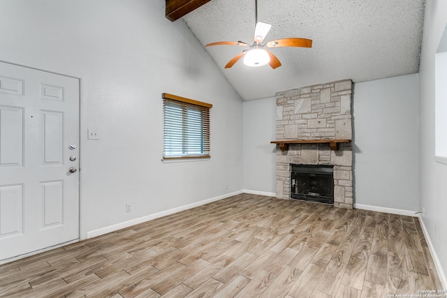 unfurnished living room with light hardwood / wood-style floors, vaulted ceiling with beams, a stone fireplace, and ceiling fan