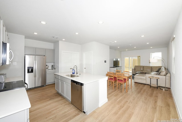 kitchen featuring appliances with stainless steel finishes, sink, gray cabinetry, and a kitchen island with sink