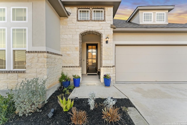 exterior entry at dusk featuring a garage