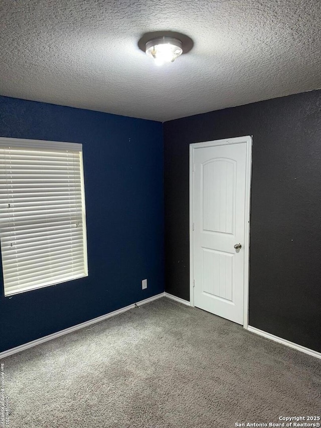 carpeted spare room with a textured ceiling