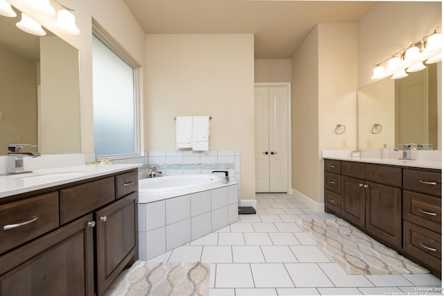 bathroom featuring tiled tub, vanity, and tile patterned floors