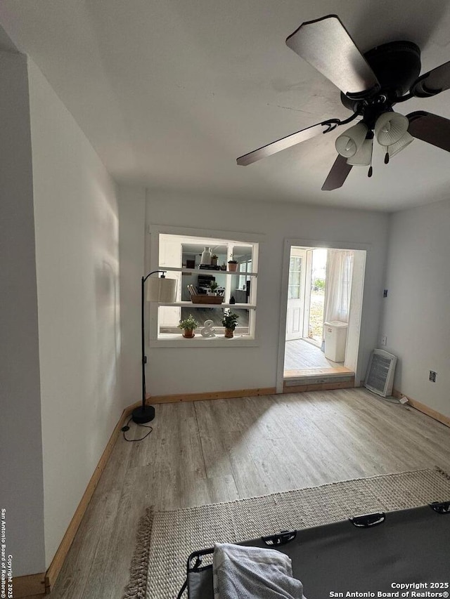 interior space featuring ceiling fan, baseboards, and wood finished floors