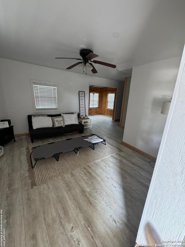 living room with a ceiling fan, baseboards, and light wood finished floors