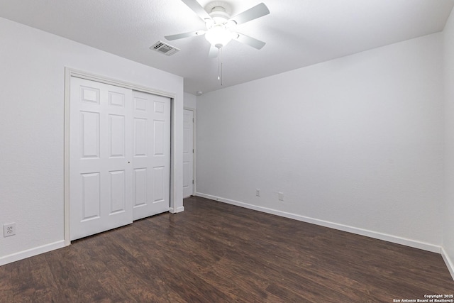 unfurnished bedroom featuring dark hardwood / wood-style flooring, ceiling fan, and a closet