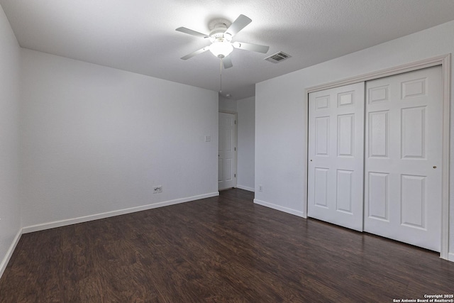 unfurnished bedroom featuring ceiling fan, dark wood-type flooring, a textured ceiling, and a closet