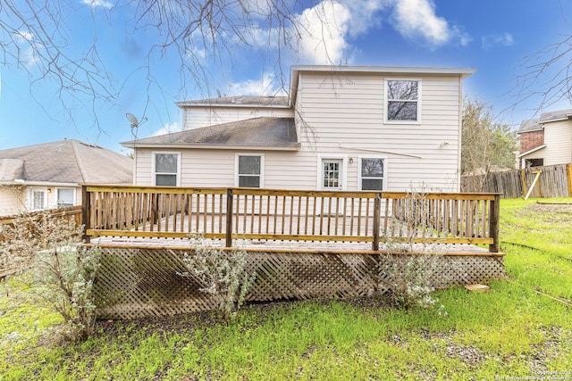 rear view of house featuring a wooden deck and a lawn