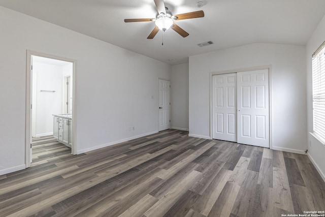 unfurnished bedroom featuring a closet, lofted ceiling, ensuite bathroom, ceiling fan, and dark hardwood / wood-style flooring