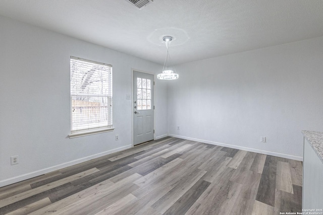 unfurnished room with a textured ceiling, wood-type flooring, and a notable chandelier