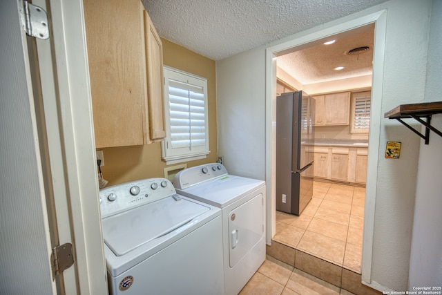 washroom with light tile patterned flooring, cabinets, a textured ceiling, and washing machine and clothes dryer