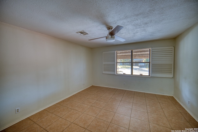 empty room featuring a textured ceiling, ceiling fan, and light tile patterned floors