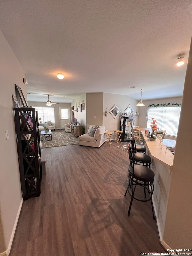 living room featuring a textured ceiling, dark hardwood / wood-style floors, and ceiling fan