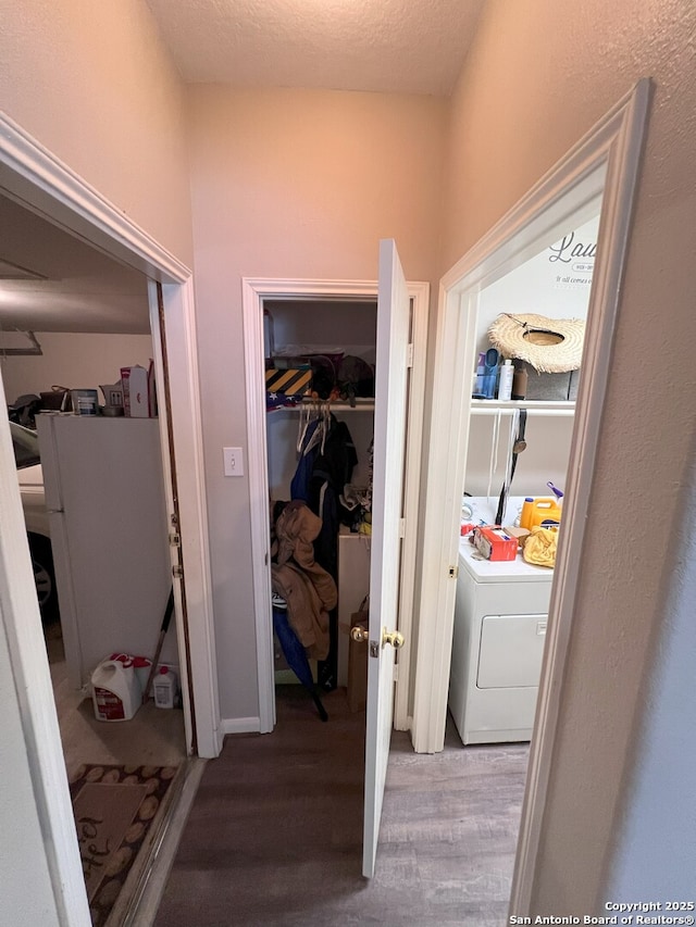 hall with a textured ceiling, washer / dryer, and wood-type flooring