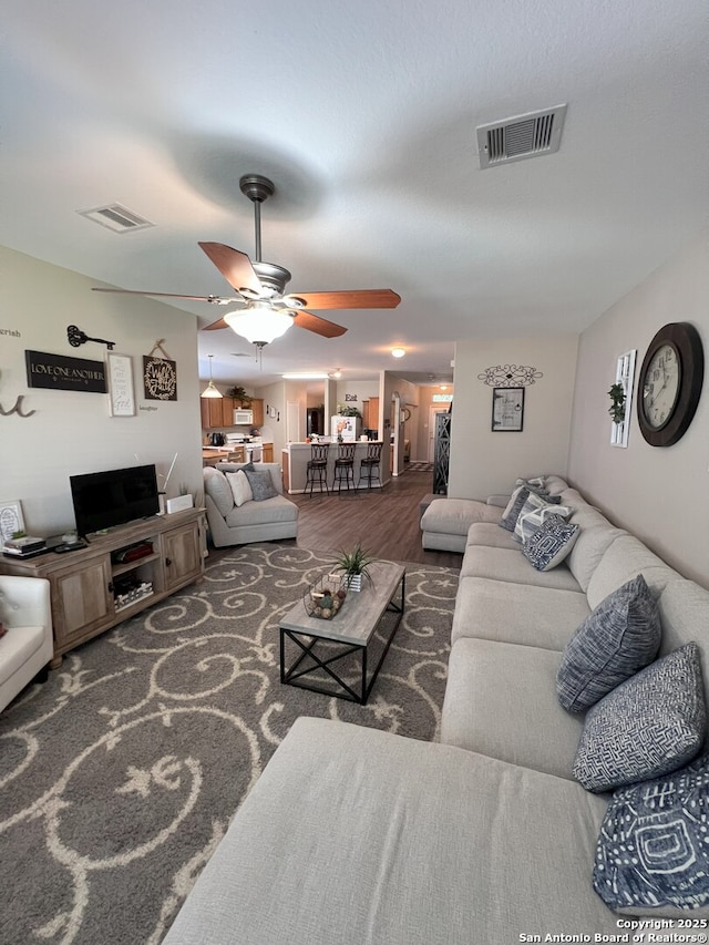 living room with dark wood-type flooring and ceiling fan