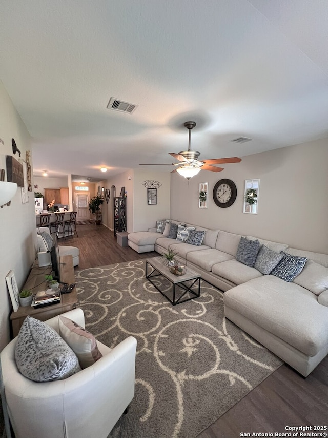 living room featuring ceiling fan and dark hardwood / wood-style flooring