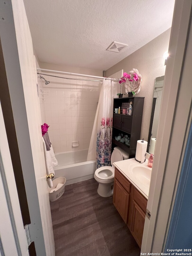 full bathroom with shower / tub combo with curtain, hardwood / wood-style flooring, toilet, a textured ceiling, and vanity