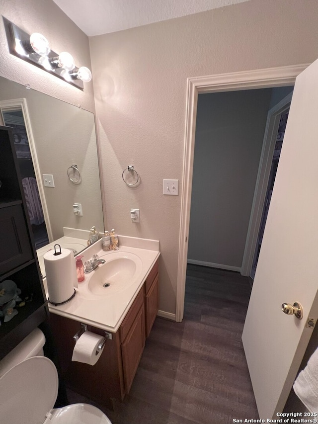 bathroom with hardwood / wood-style flooring, vanity, and toilet